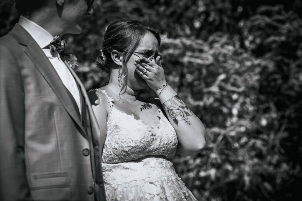 La mariée, main sur la bouche, retenant ses larmes