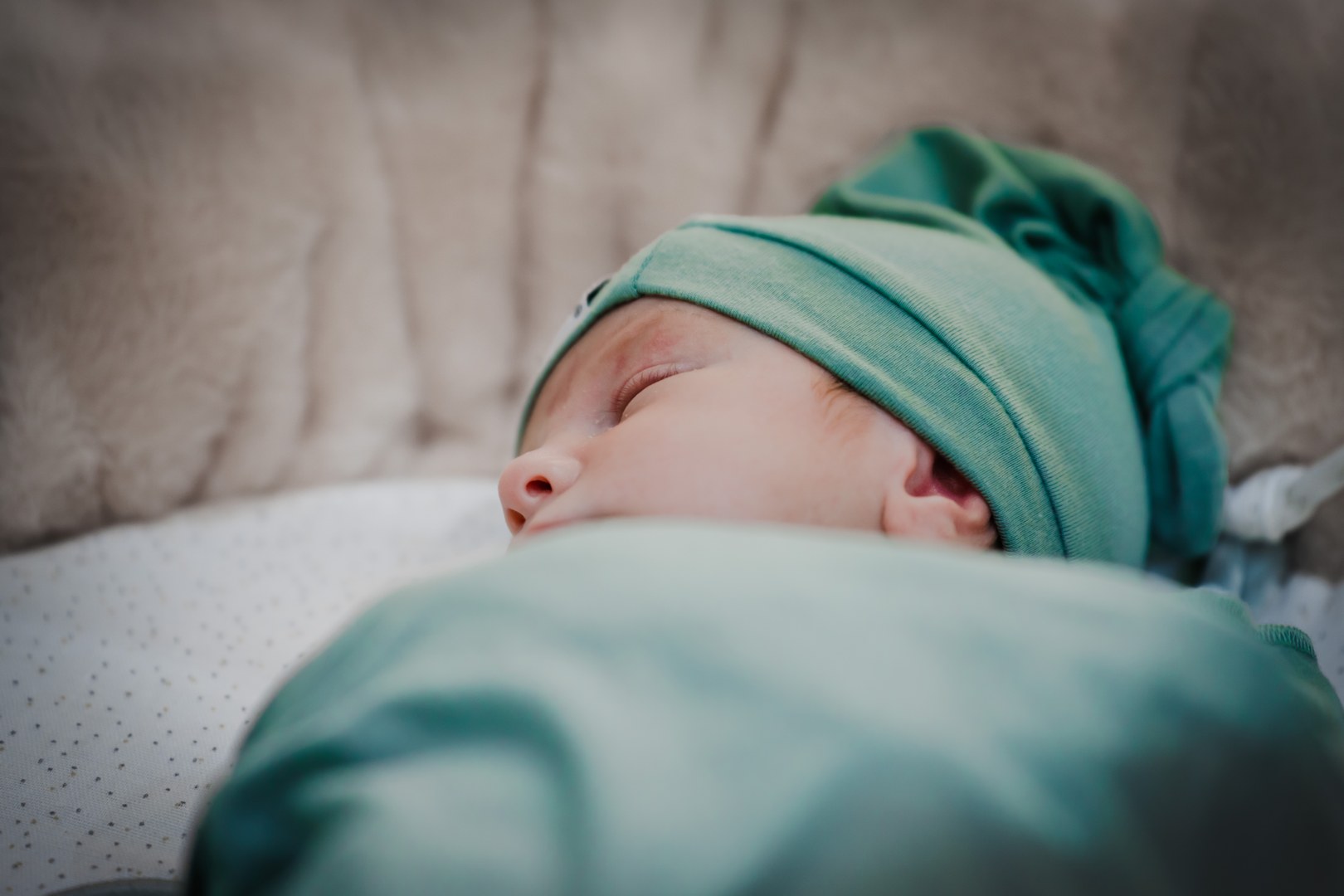 Nouveau-né endormi avec un bonnet vert