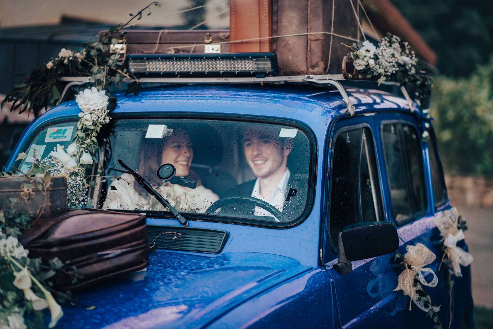 Couple en voiture 4L bleue sous la pluie