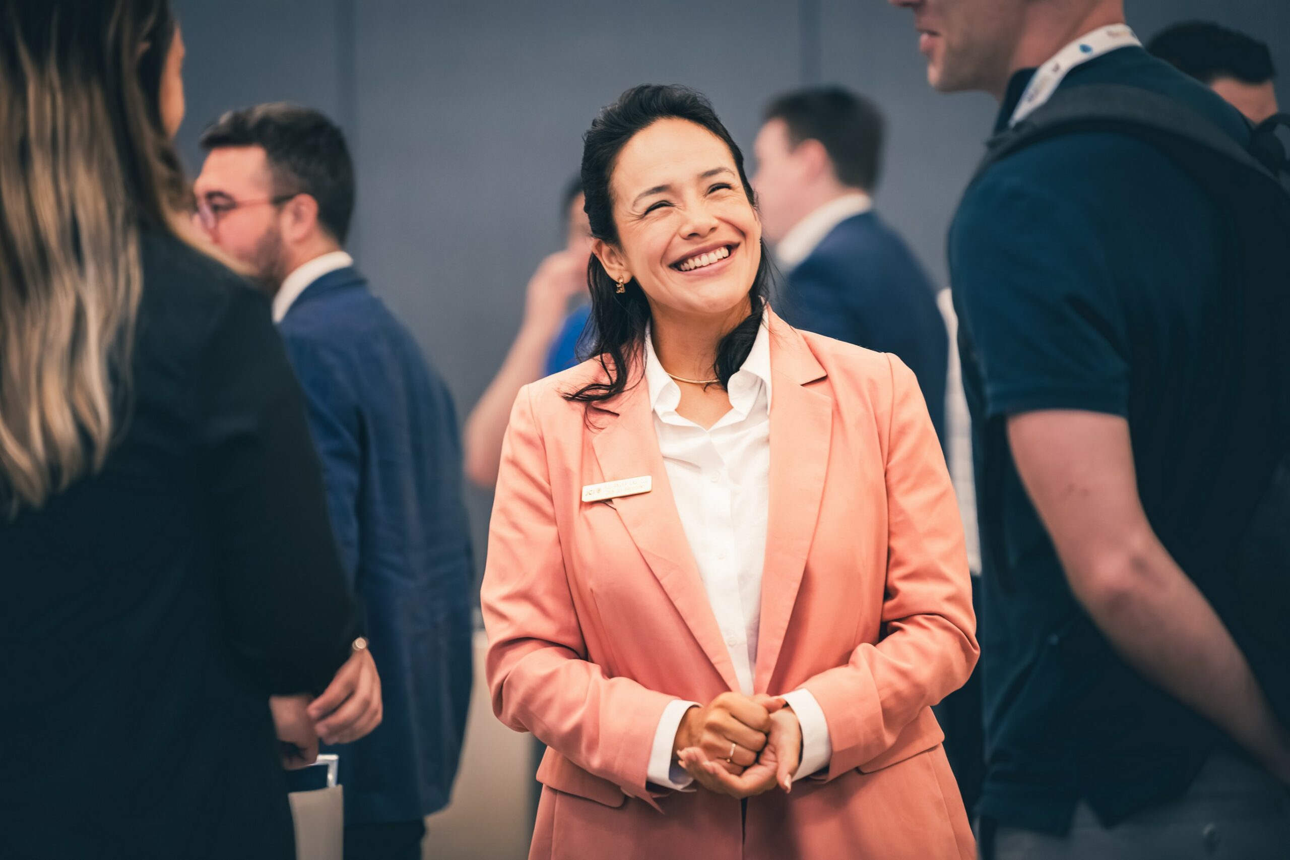 Participante souriante échangeant avec d’autres personnes lors d’un évènement professionnel
